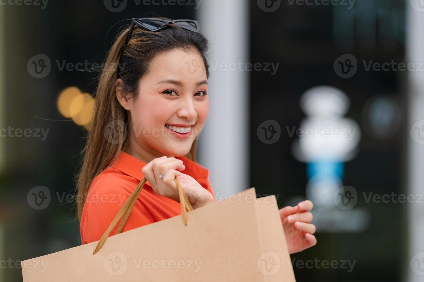 Außenporträt der glücklichen Frau, die Einkaufstaschen hält foto