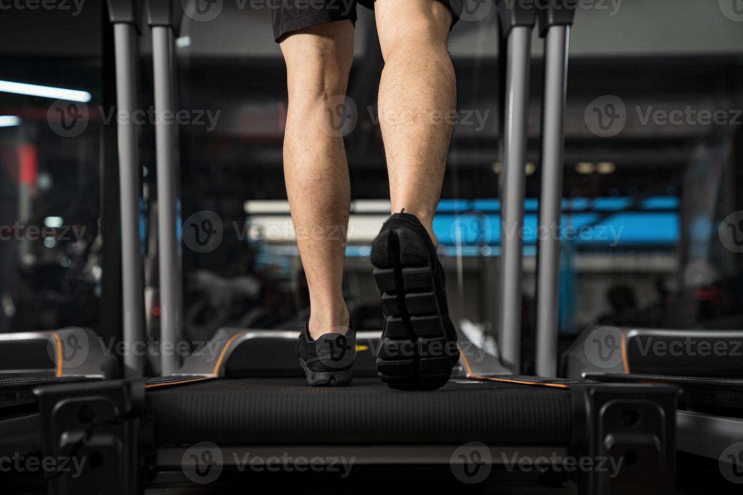 Nahaufnahme von männlichen Beinen, die auf dem Laufband im Fitnessstudio laufen? foto