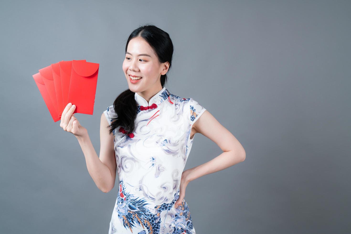 asiatische Frau trägt chinesisches traditionelles Kleid mit rotem Umschlag oder rotem Paket foto