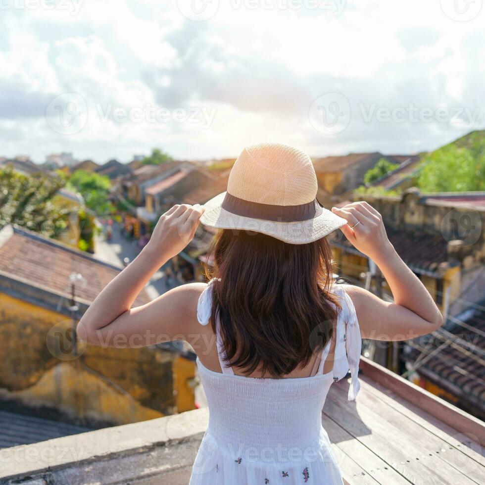 glücklich Reisender Reisen beim hoi ein uralt Stadt, Dorf im Vietnam, Frau mit Kleid und Hut Besichtigung Aussicht beim Dach.Wahrzeichen und Beliebt zum Tourist Sehenswürdigkeiten. Vietnam und Süd-Ost Asien Reise Konzept foto