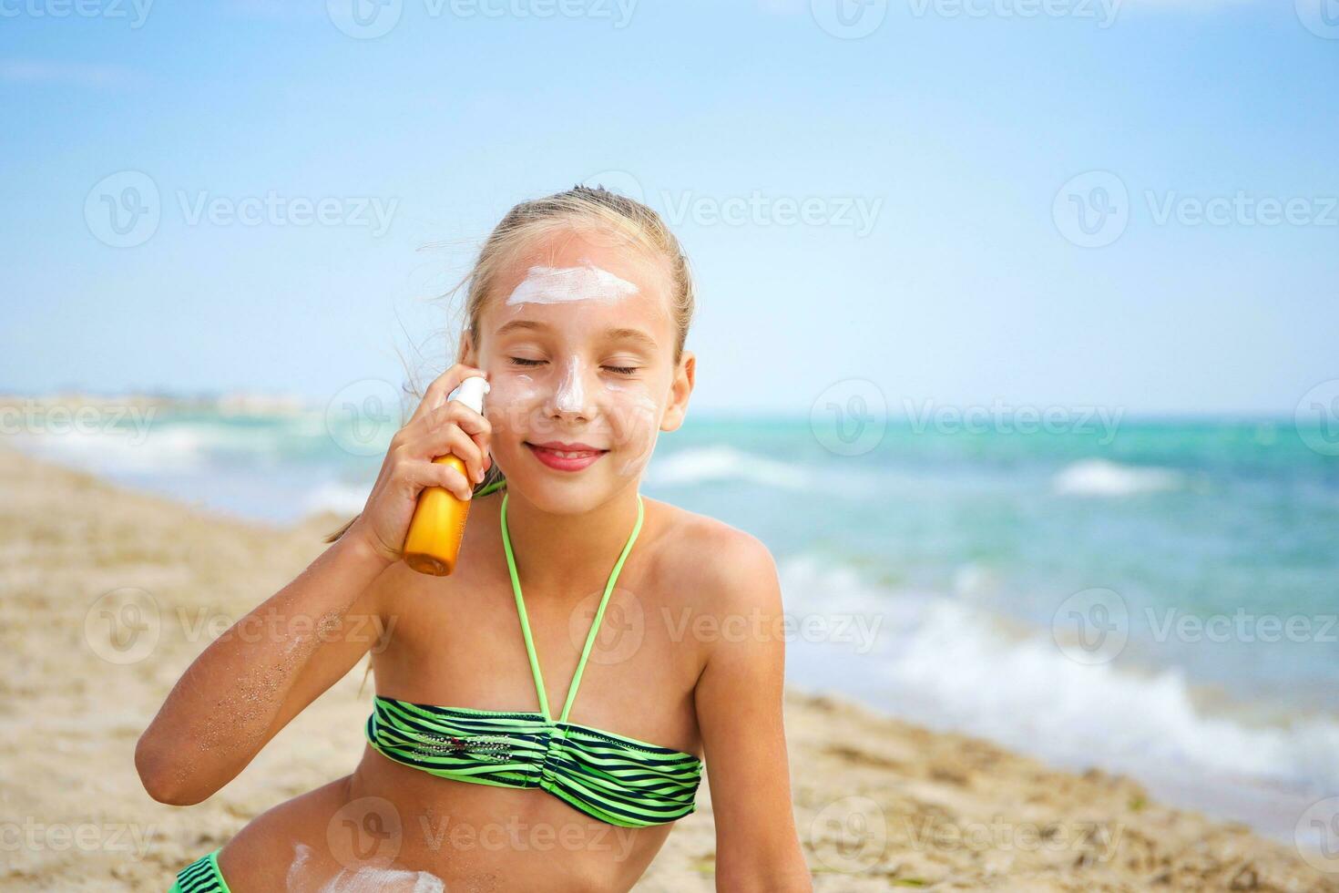 Mädchen bewirbt sich schützend Sonnenschutz auf Gesicht. foto