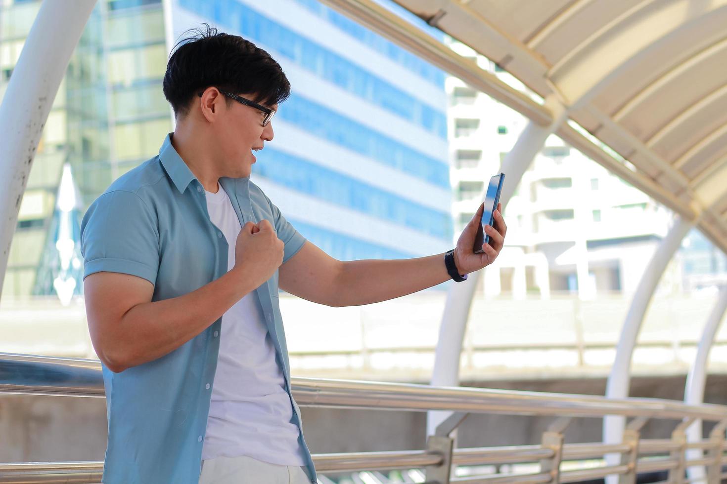 Porträt gutaussehender Mann benutzt ein Smartphone und scheint glücklich zu sein, dass es einen Gebäudehintergrund und moderne Gebäude gibt foto