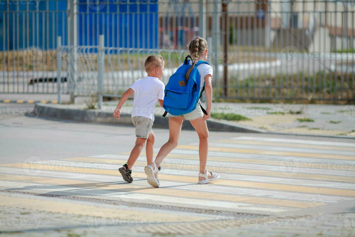 Bruder und Schwester Lauf über ein Fußgänger Kreuzung. Kinder Lauf entlang das Straße zu Kindergarten und Schule.Zebra der Verkehr gehen Weg im das Stadt. Konzept Fußgänger Vorbeigehen ein Zebrastreifen foto