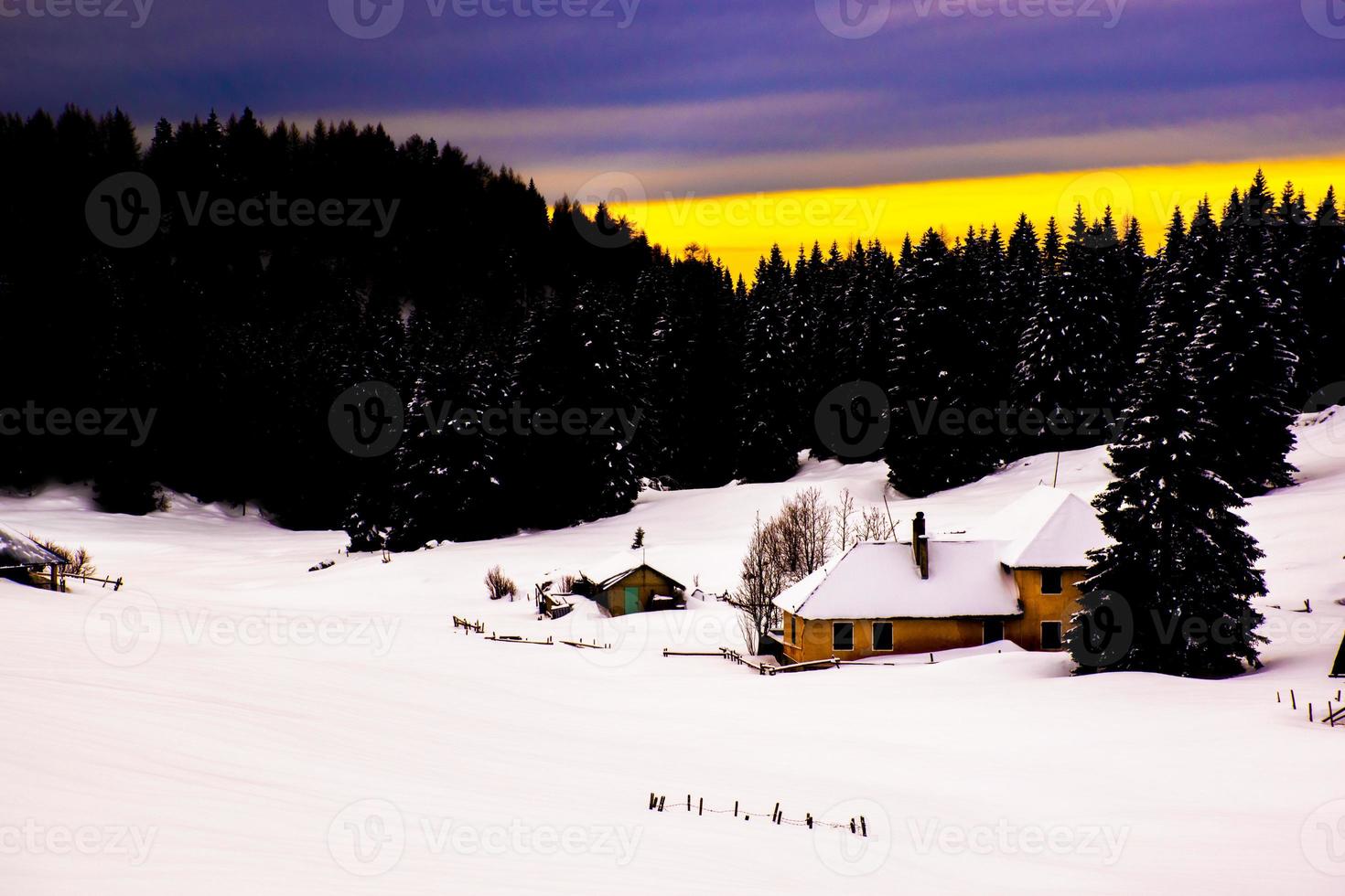 gelbes Gebäude in einer verschneiten Landschaft bei Sonnenuntergang foto
