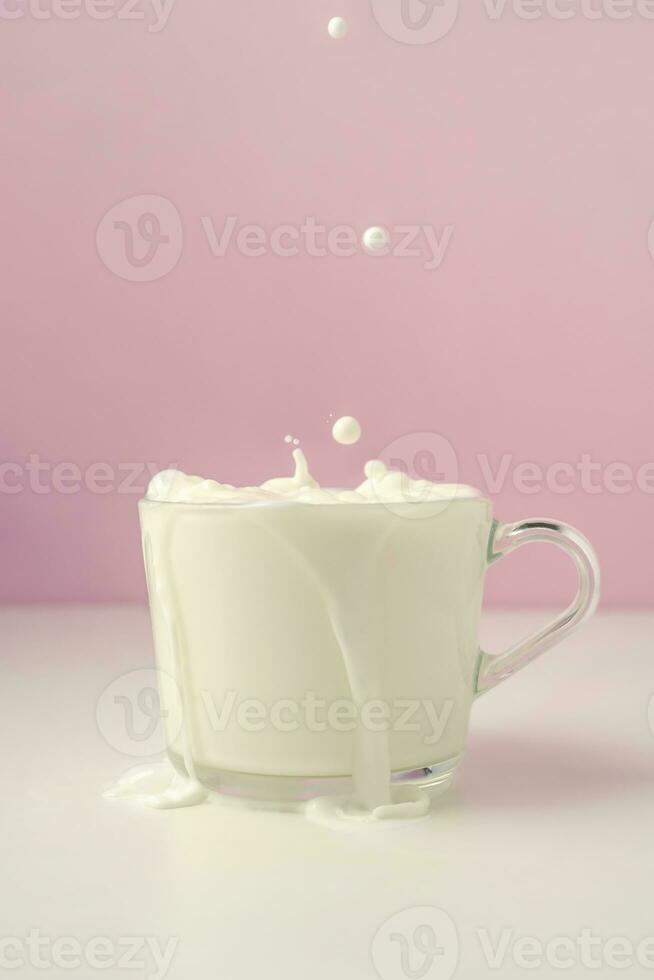 Milch ist gegossen in ein transparent Tasse auf ein lila Hintergrund. foto