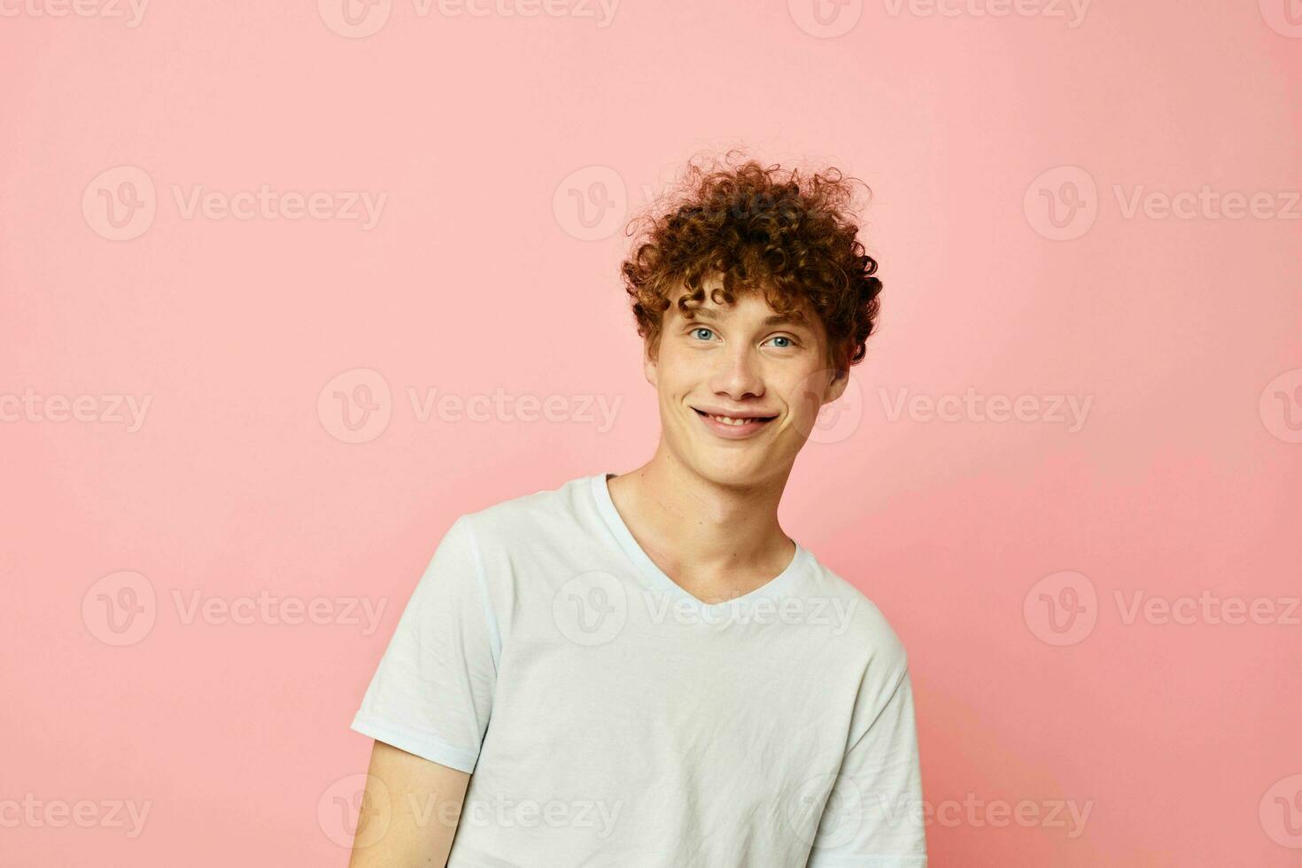 jung lockiges Haar Mann posieren Jugend Stil Weiß T-Shirt Rosa Hintergrund unverändert foto