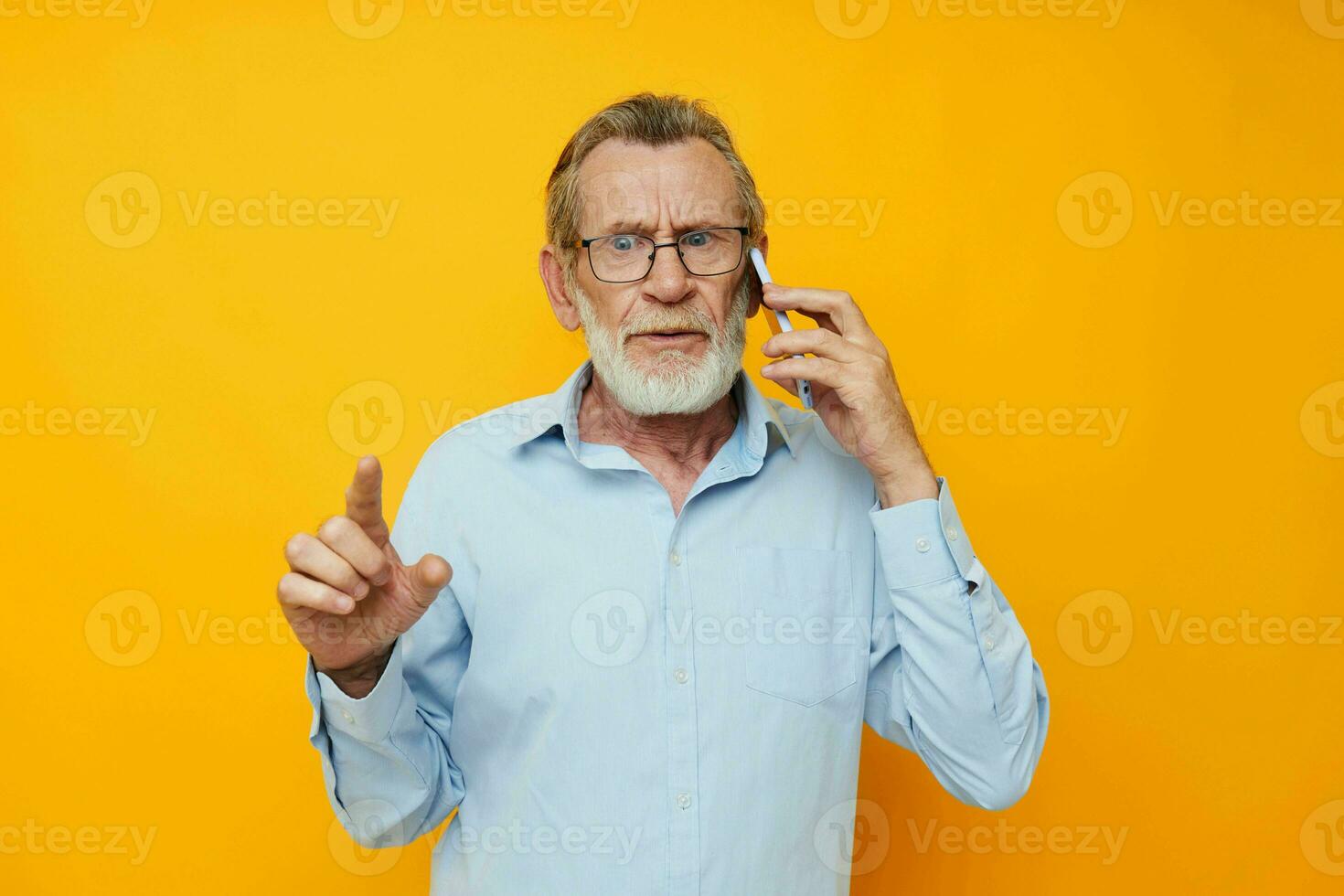 alt Mann im ein Blau Hemd und Brille reden auf das Telefon Gelb Hintergrund foto