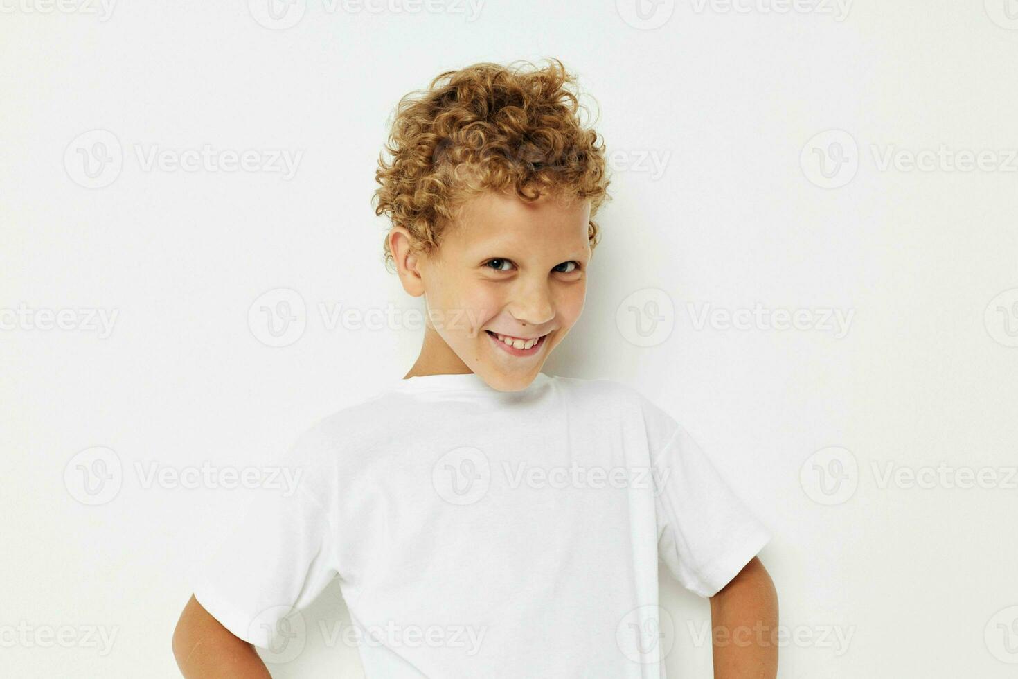 emotional Junge mit lockig Haar im ein Weiß T-Shirt schließen oben foto