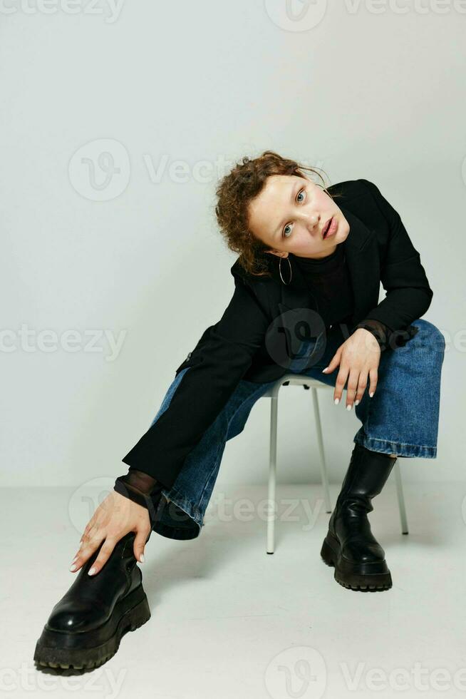 Porträt von ein jung Frau Sitzung auf ein Stuhl im ein schwarz Jacke Mode posieren Lebensstil unverändert foto