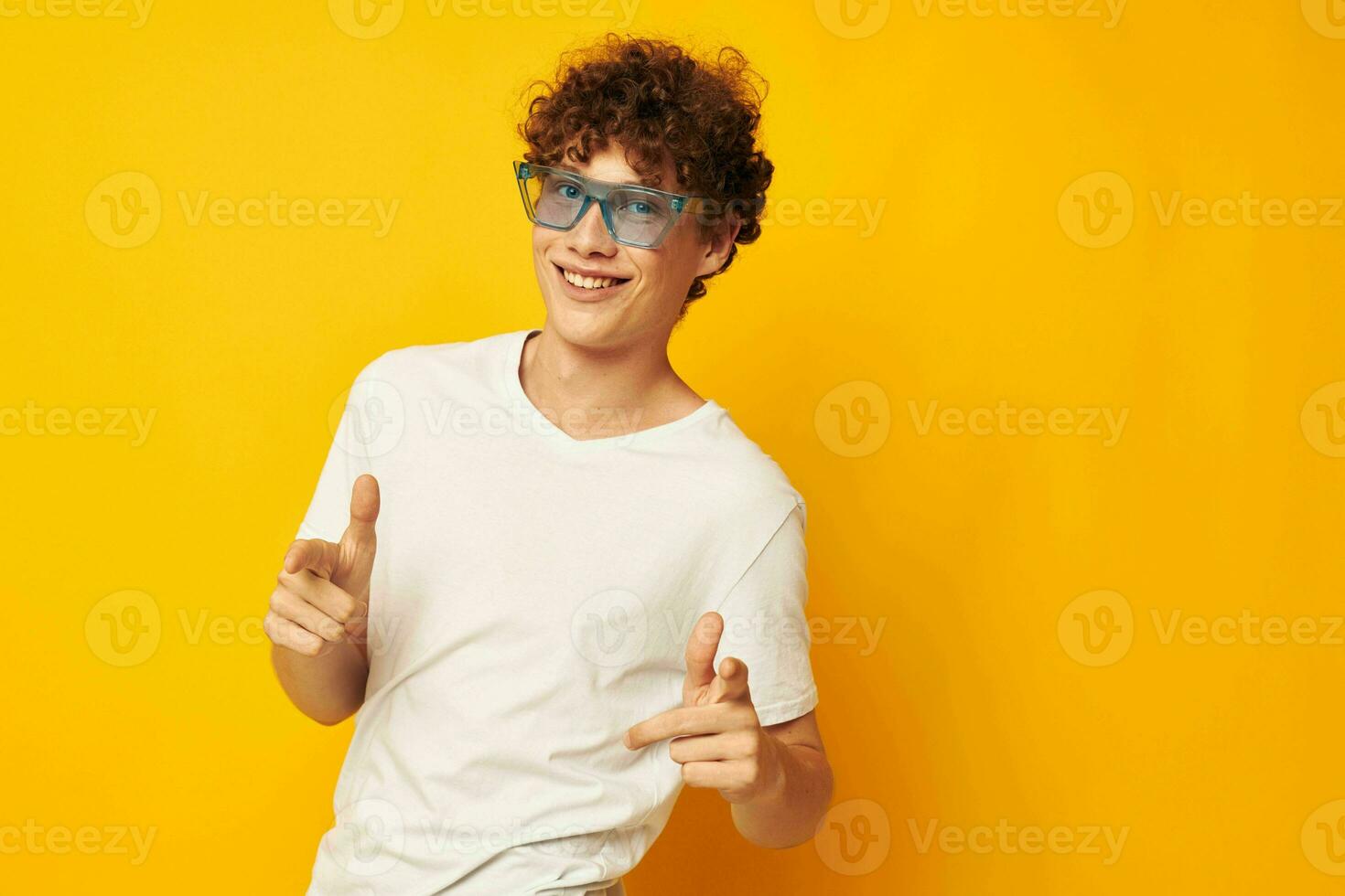 Porträt von ein jung lockig Mann im ein Weiß T-Shirt Blau Mode Brille isoliert Hintergrund unverändert foto