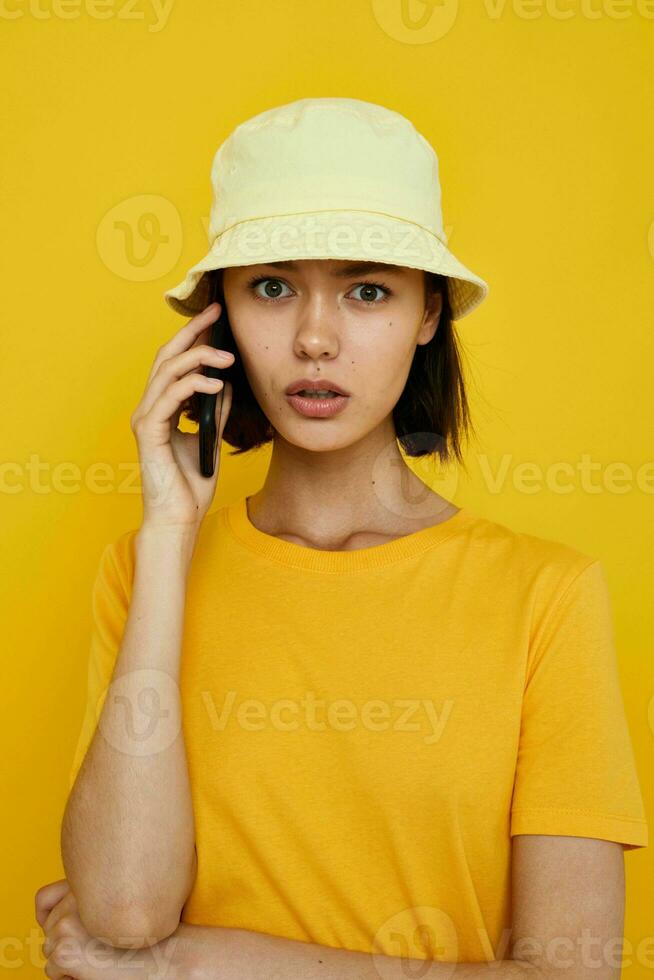 optimistisch jung Frau im ein Gelb Hut Jugend Stil beiläufig reden auf das Telefon Lebensstil unverändert foto