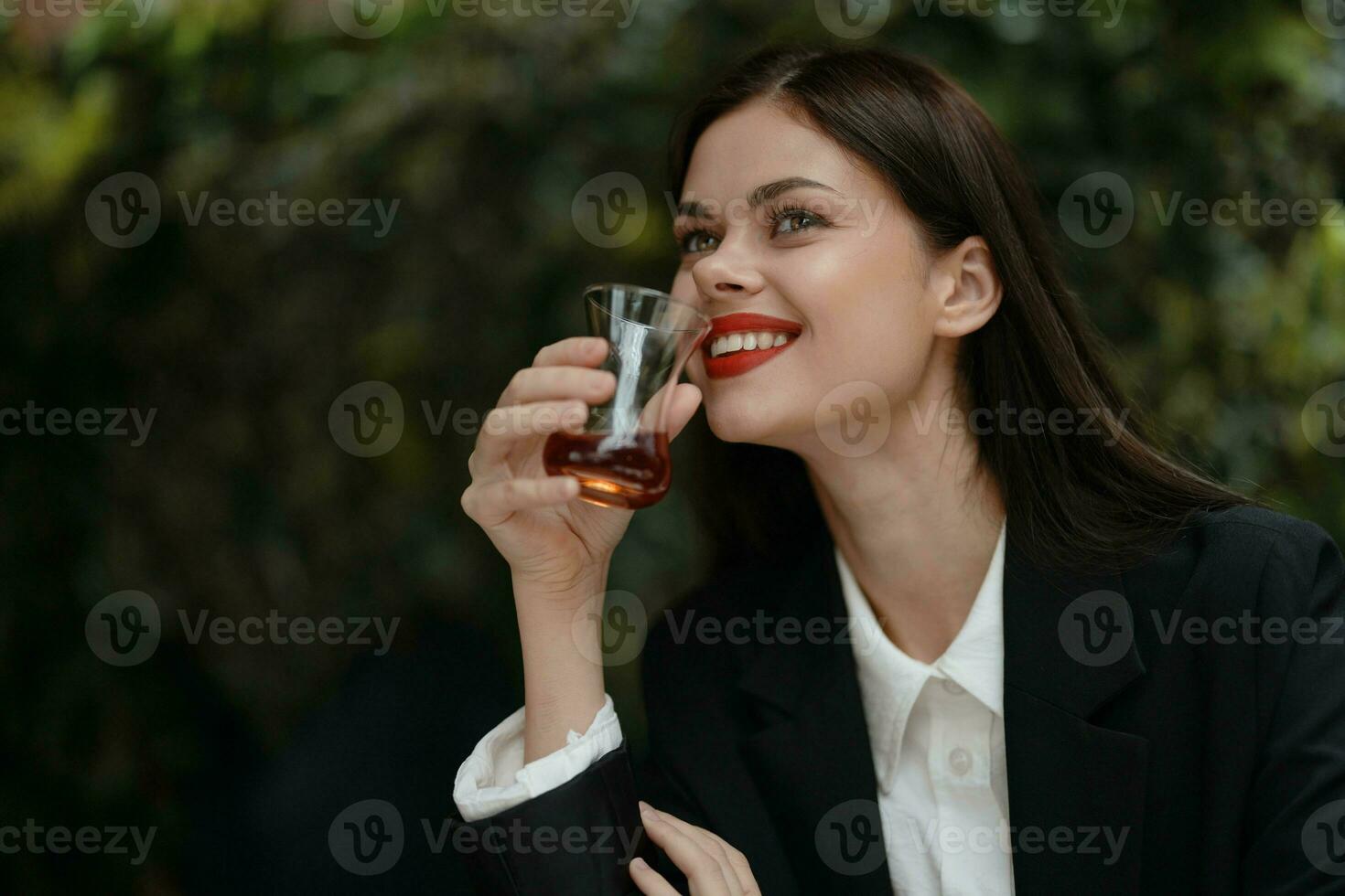 Frau Lächeln mit Zähne Trinken Tee im ein Cafe von ein Türkisch Glas Becher auf das Straße, Frühling reisen, Stadt brechen foto