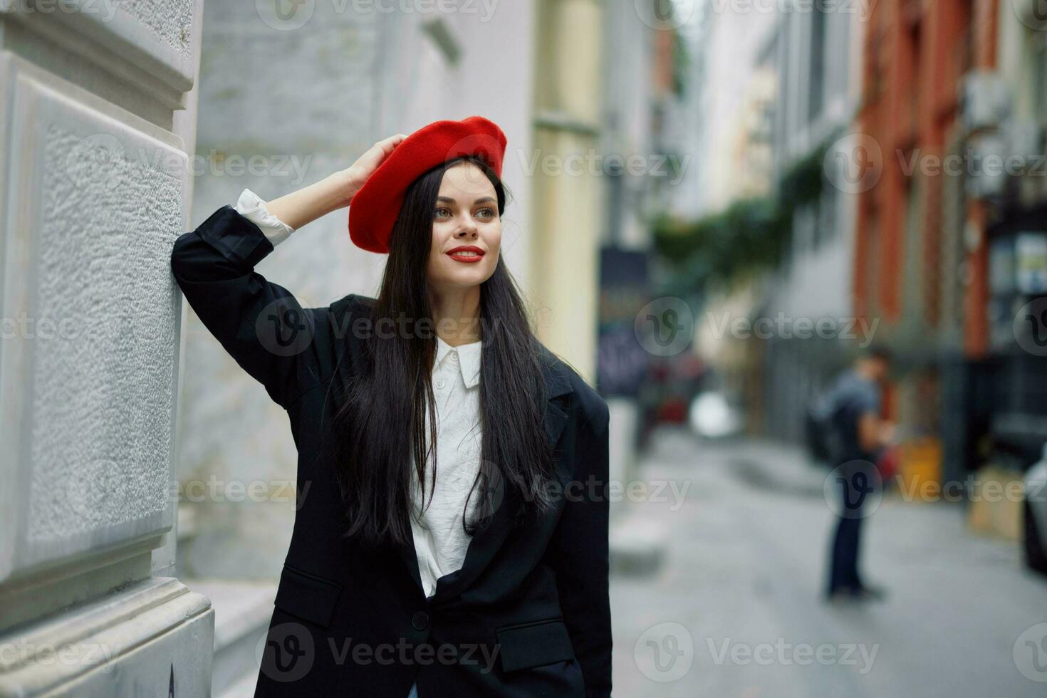 Frau Stehen in der Nähe von ein Mauer im das Stadt tragen ein stilvoll Jacke und rot Baskenmütze mit rot Lippen, Reise und Freizeit, Französisch Stil von Kleid. foto