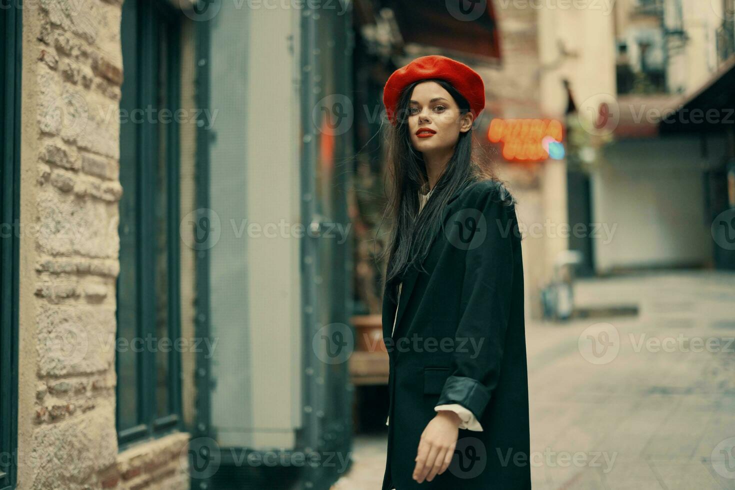 Mode Frau Tourist im stilvoll Kleider im ein Jacke und rot Baskenmütze Laufen Nieder das eng Straße von das Stadt Lächeln und Glück Reise, Französisch Stil, filmisch Farbe. foto