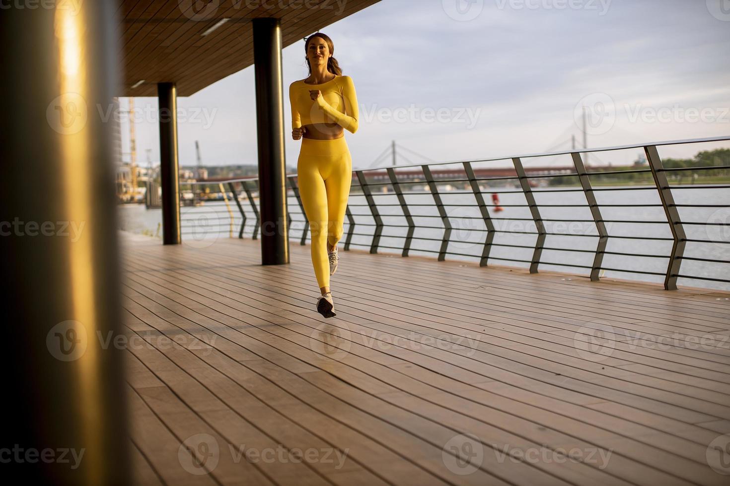 junge Frau beim Lauftraining an der Flusspromenade foto