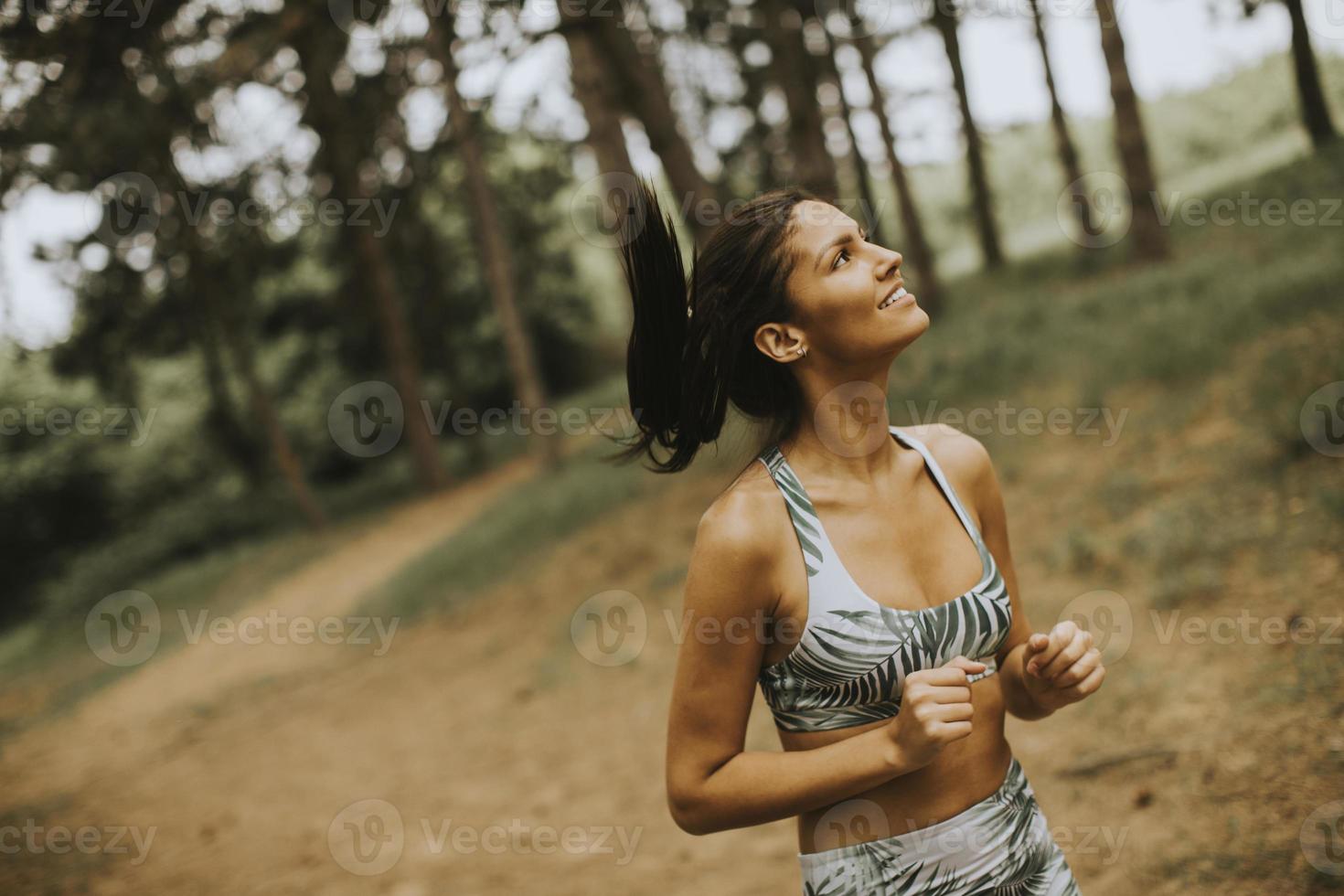 junge Fitnessfrau, die am Waldweg läuft foto