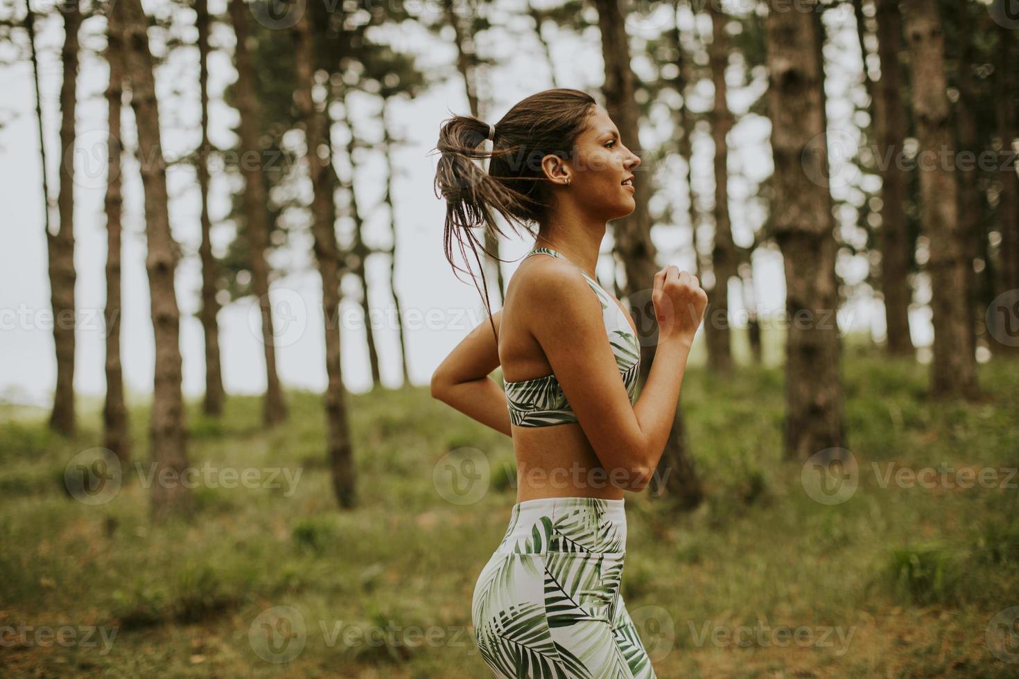 junge Fitnessfrau, die am Waldweg läuft foto