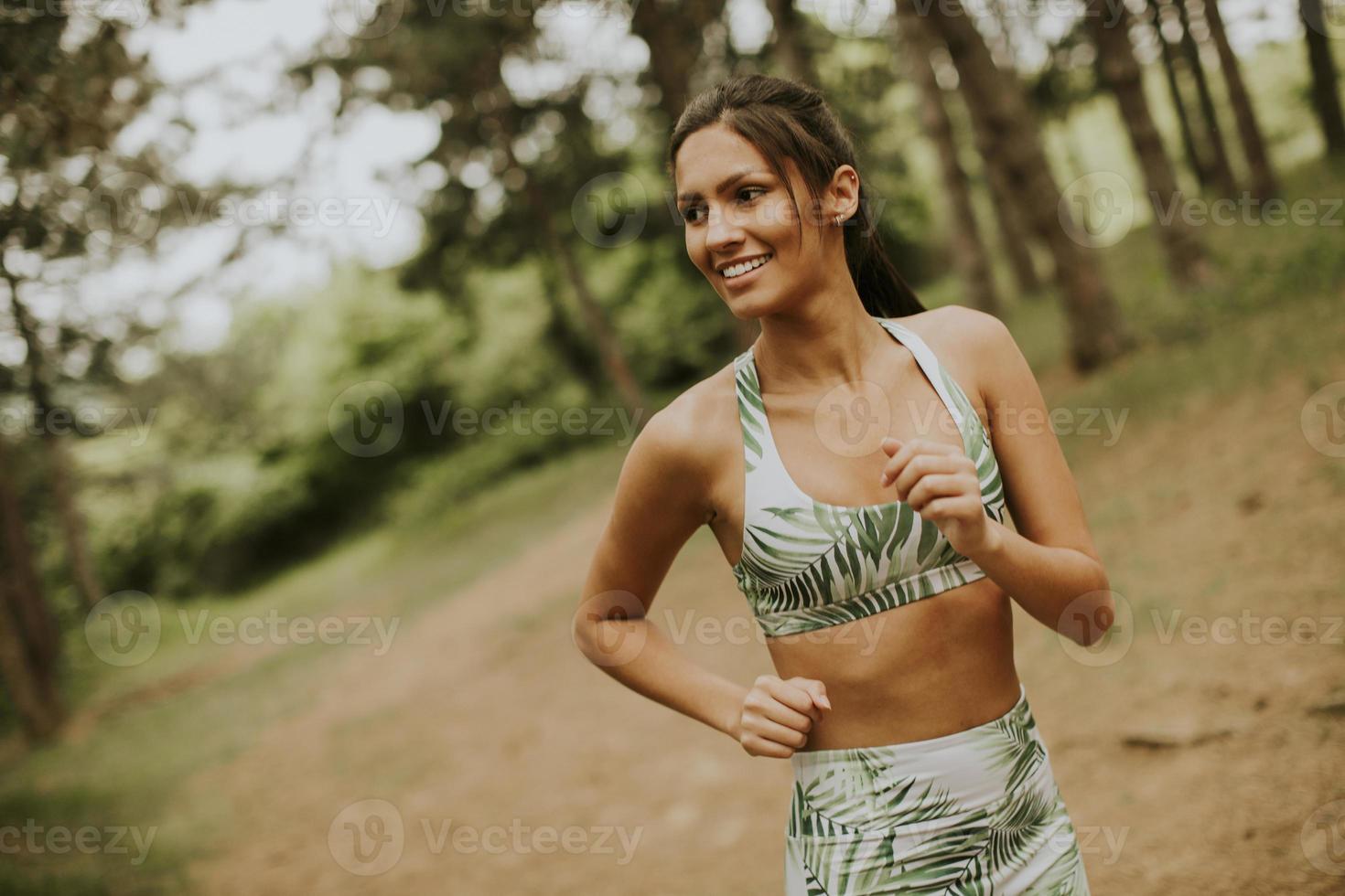 junge Fitnessfrau, die am Waldweg läuft foto