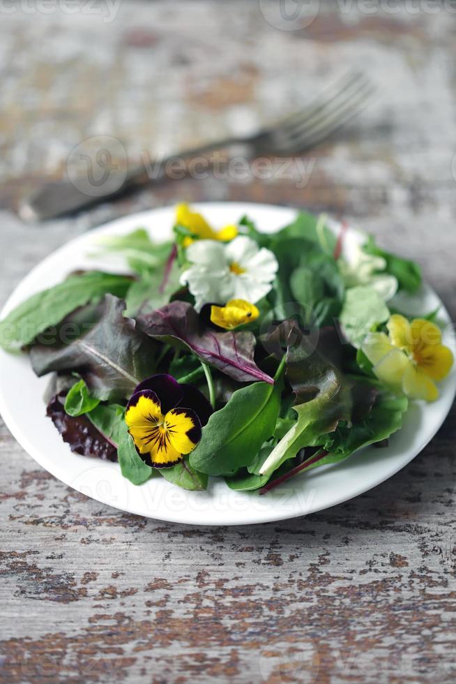 Salatmischung mit Blumen auf einem weißen Teller foto