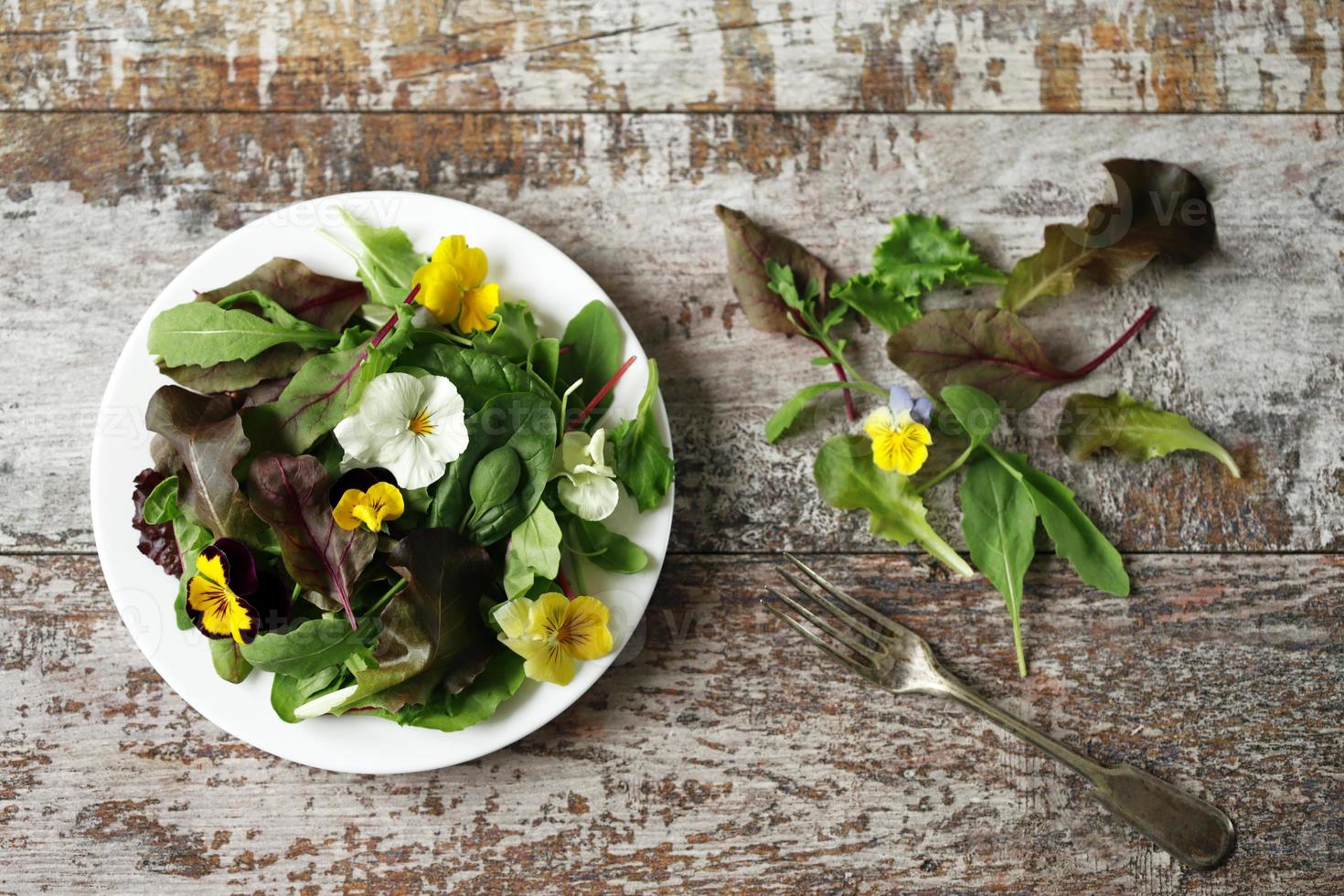 Salatmischung mit Blumen auf einem weißen Teller foto