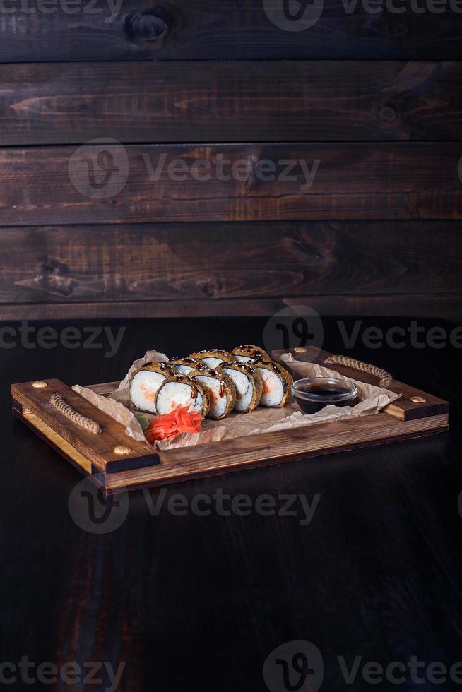 Meeresfrüchterollen auf einem Holztablett, schöne Portion, dunkler Hintergrund foto