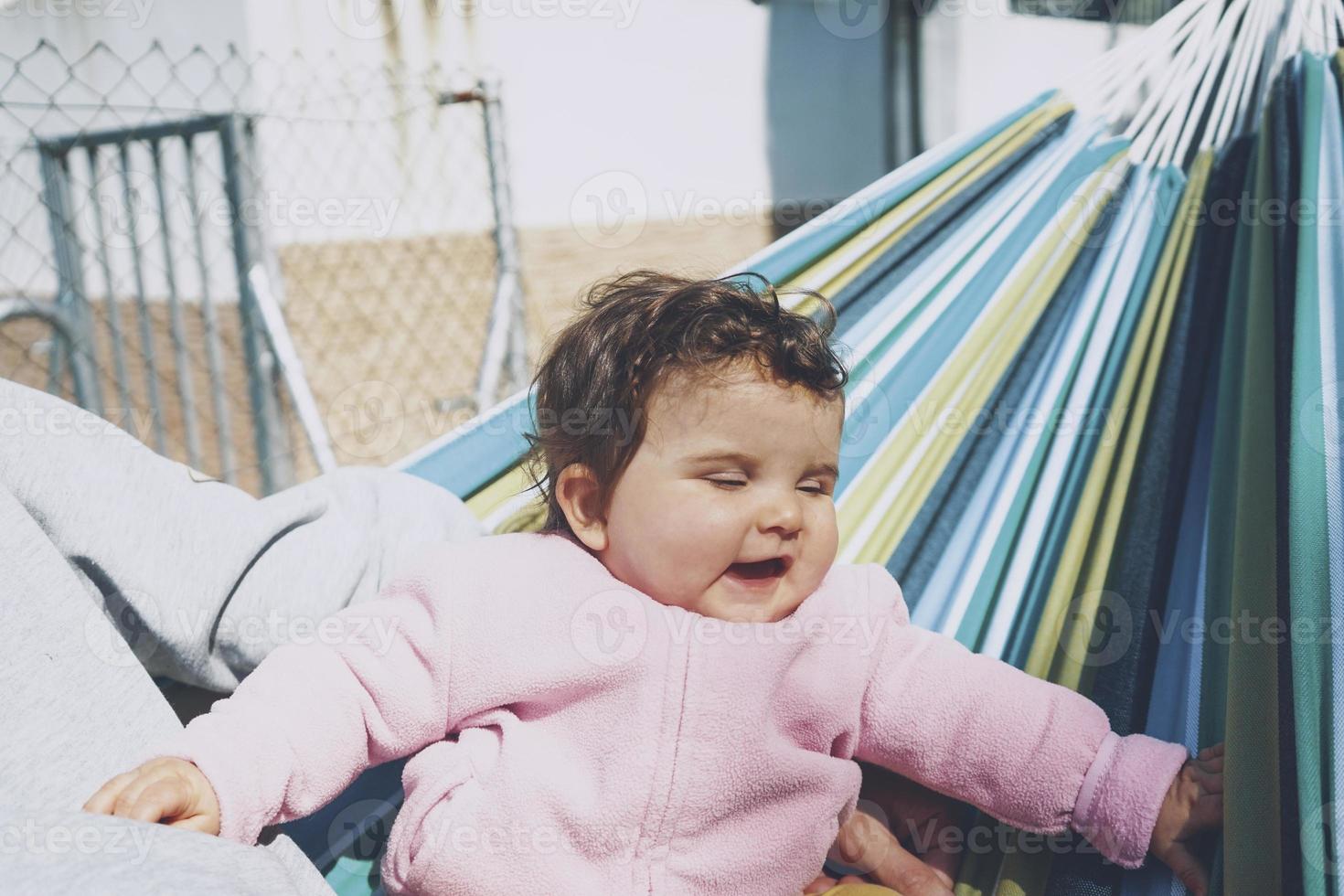 kleines Baby, das an einem sonnigen Tag Spaß in einer Hängematte hat foto
