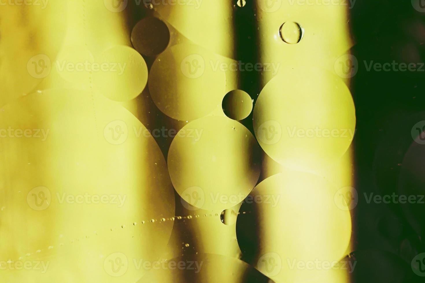 ein schönes und lebendiges Makro von Ölblasen auf dem Wasser mit einer gelben und schwarzen Streifenstruktur als Hintergrundmuster mit Vintage-Filter foto