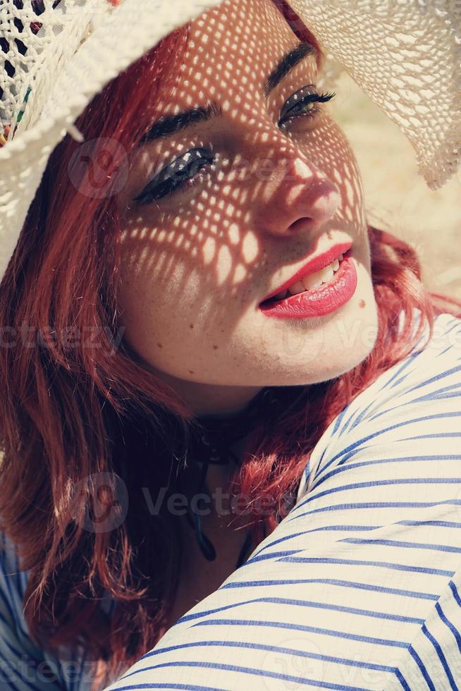 junge rothaarige Frau, die sich vor der Sonne bedeckt foto