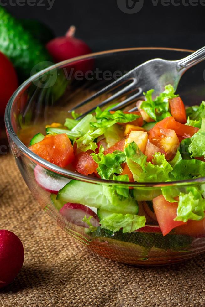 Salat aus frischem Gemüse in einer Glasschüssel auf dunklem Hintergrund veganes Bio-Lebensmittel saisonales Sommergericht foto