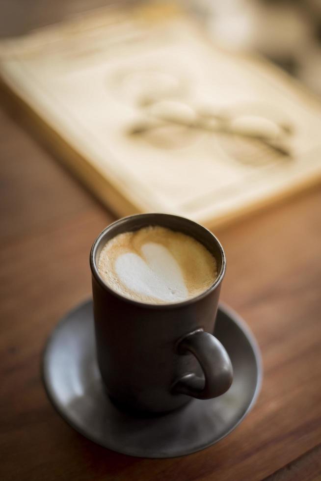 heiße Latte Art mit schwarzem Glas auf Holztisch foto