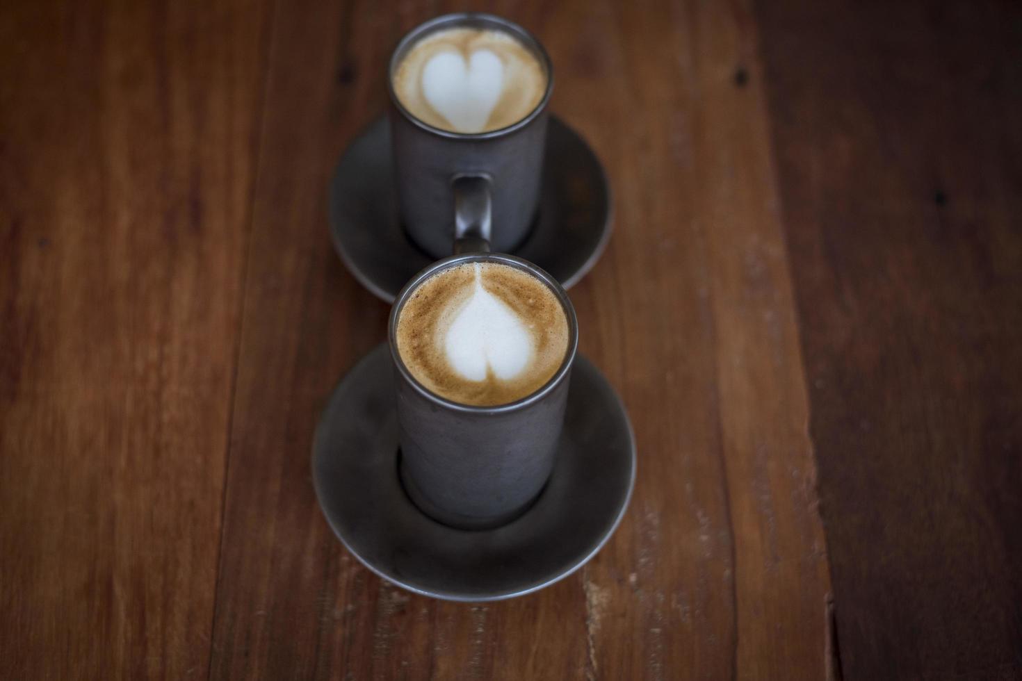 heiße Latte Art mit schwarzem Glas auf Holztisch foto