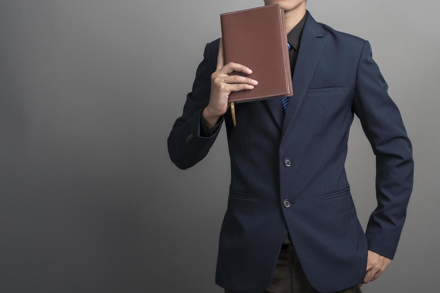 Nahaufnahme eines Geschäftsmannes im blauen Anzug mit Büchern auf grauem Hintergrund holding foto