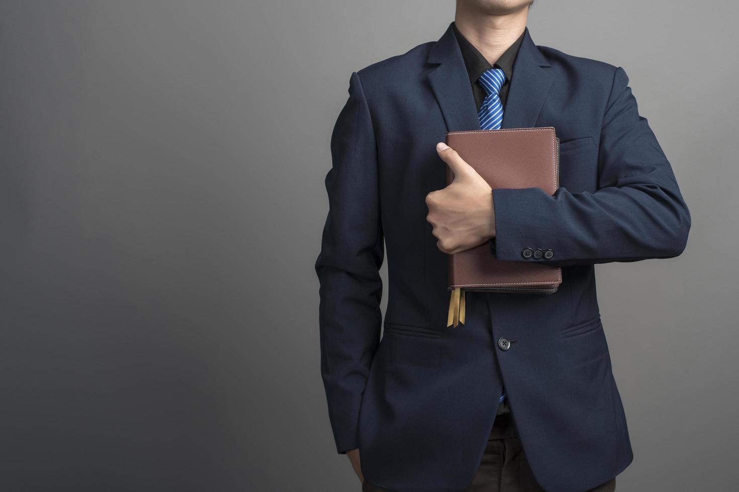 Nahaufnahme eines Geschäftsmannes im blauen Anzug mit Büchern auf grauem Hintergrund holding foto