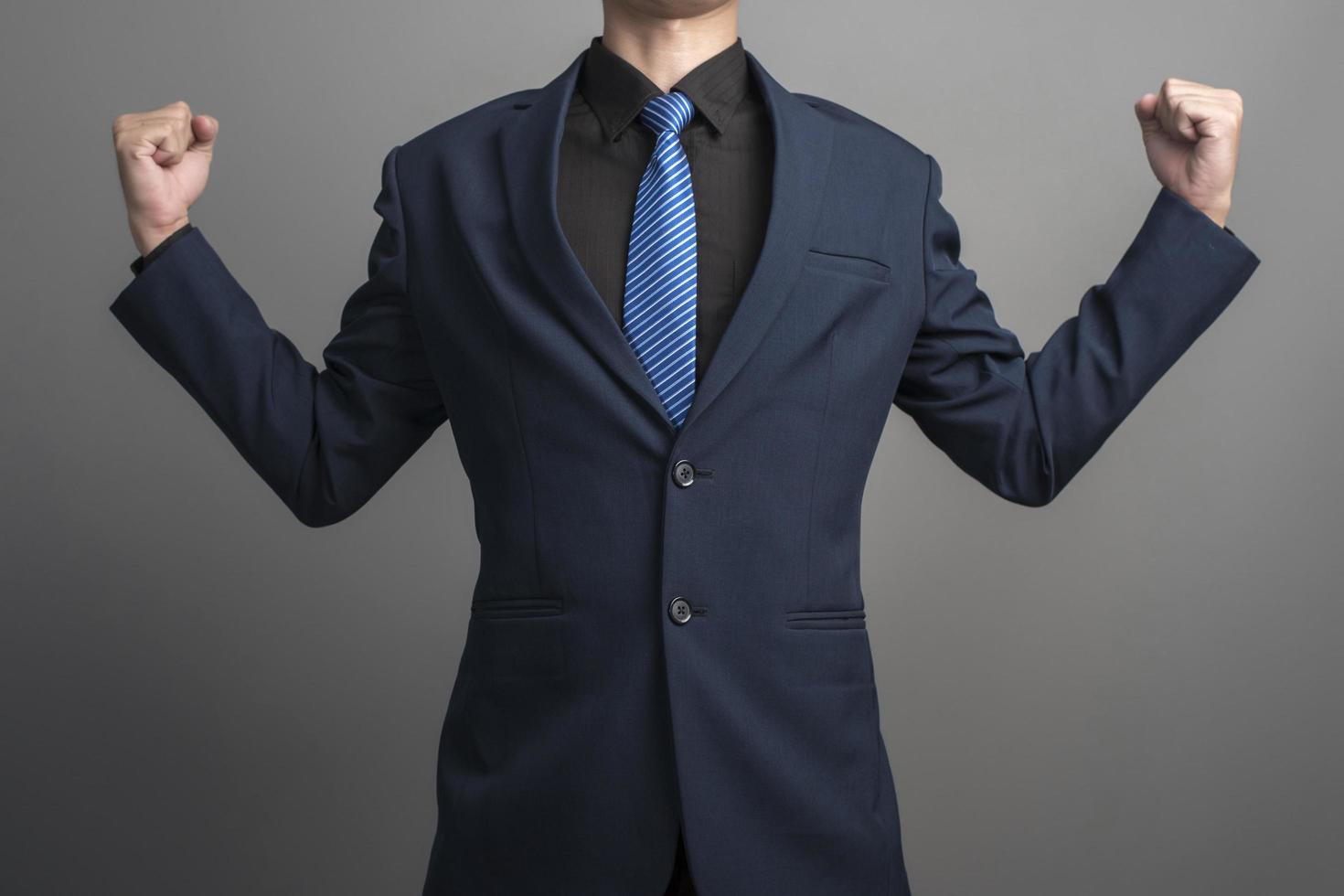 Nahaufnahme eines Geschäftsmannes im blauen Anzug, der auf grauem Hintergrund kämpft foto