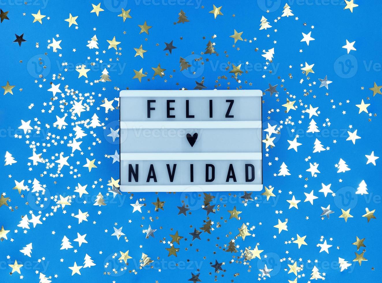 Leuchtkasten mit Feliz Navidad Phrase, spanische Frohe Weihnachten auf blauem Hintergrund mit Konfetti. foto