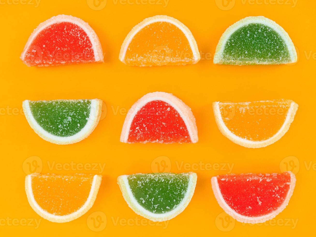 Mehrfarbige Marmelade Zitrusscheiben in Zucker auf orangem Hintergrund. foto