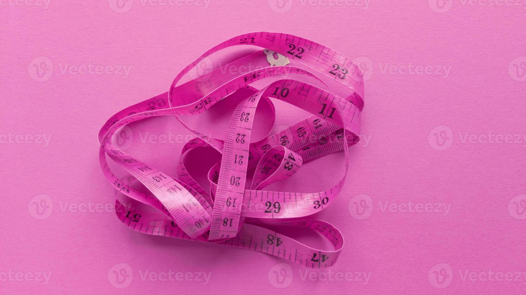 rosa Zentimeter auf rosa Hintergrund. einfache flache Lage mit pastellfarbener Textur. Fitnesskonzept. Stock Foto. foto