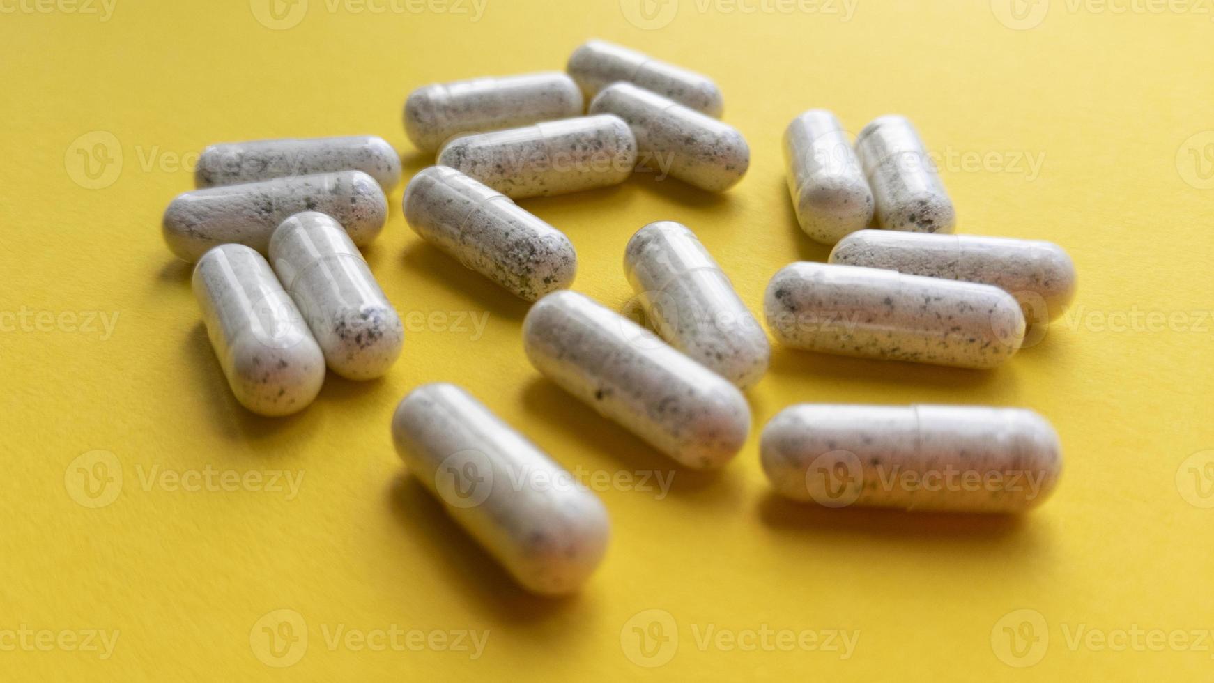 weiße Pille Kapseln auf gelbem Hintergrund. einfache flache Lage mit pastellfarbener Textur. medizinisches Konzept. Stock Foto. foto