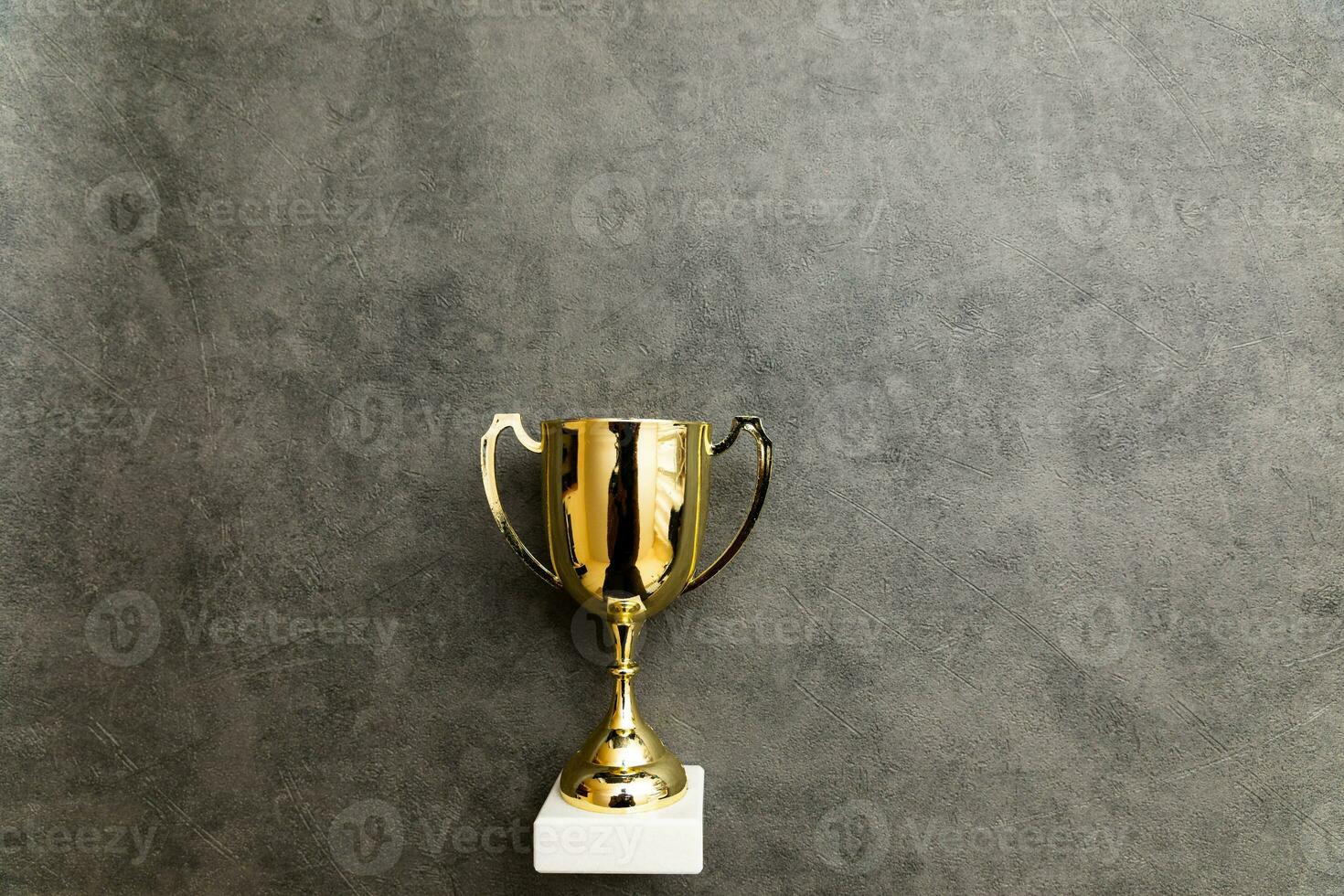 Einfach flach liegen Design Gewinner oder Champion Gold Trophäenpokal auf betonsteingrauem Hintergrund. Sieg erster Platz des Wettbewerbs. gewinn- oder erfolgskonzept. Kopierbereich von oben. foto