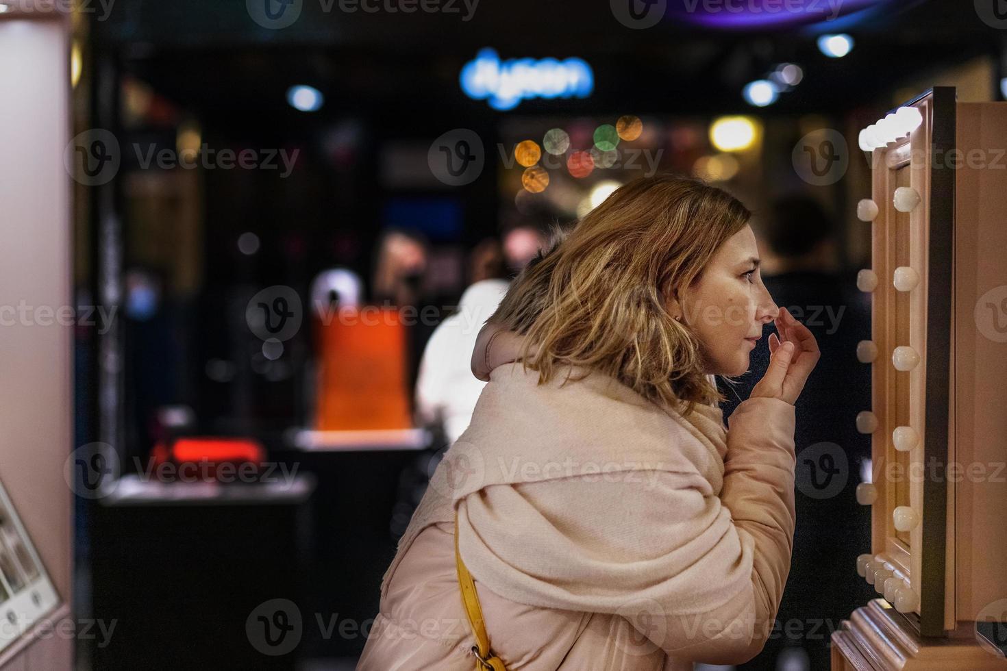 Eine junge Frau vor einem Spiegel passt ihr Make-up an foto