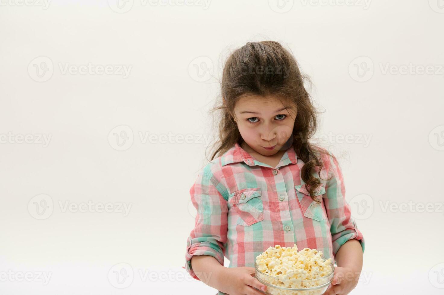 schön Baby Mädchen im stilvoll Rosa und Blau Plaid Shirt, halten Schüssel mit köstlich Popcorn, isoliert auf Weiß Hintergrund foto