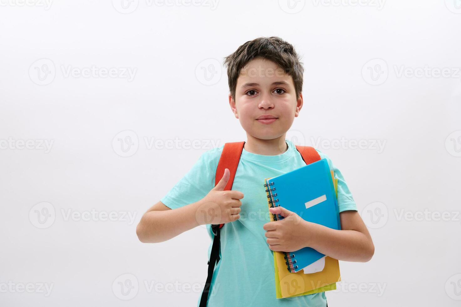 Clever Schule Kind, gut aussehend preteen Junge lächelt suchen beim Kamera, Daumen hoch, zeigen die Genehmigung Zeichen auf Weiß Hintergrund foto