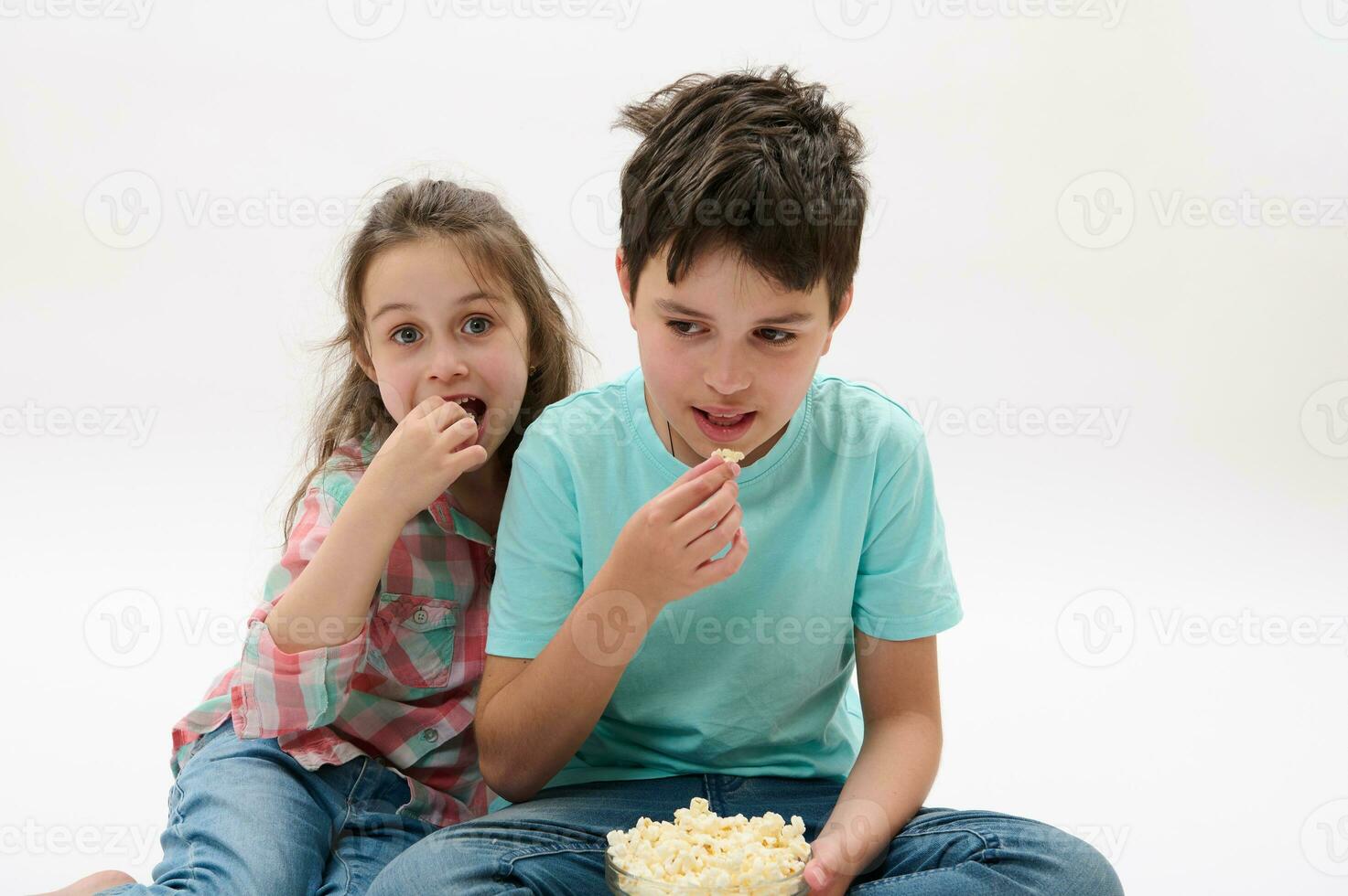 glücklich Kinder, Junge und Mädchen Essen Popcorn, Aufpassen Film, lächelnd suchen beim Kamera, isoliert auf Weiß Studio Hintergrund foto