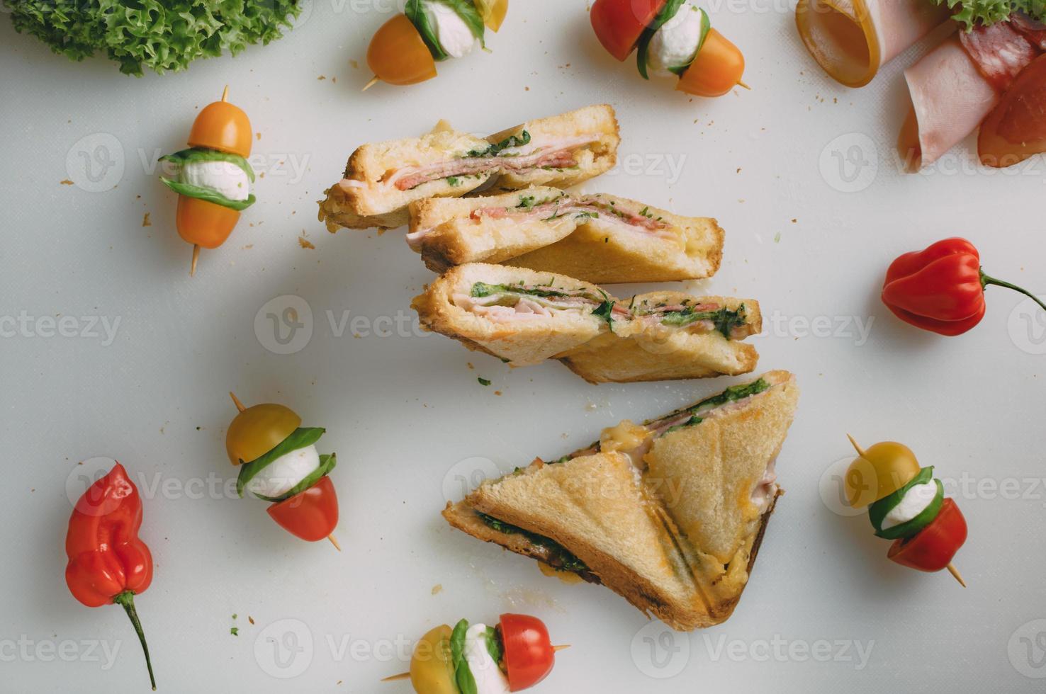 Club Sandwich mit Schinken, Salami, geräuchertem Rindfleisch, Käse, Salat und Rucola. Toast-Sandwich-Zubereitung. Ansicht von oben. foto