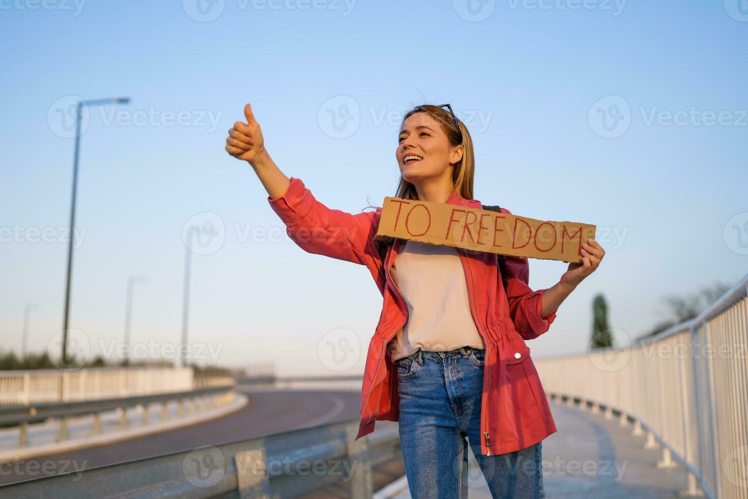 Frau ist Trampen auf Straßenrand versuchen zu halt Wagen. sie ist halten Karton mit Inschrift. foto