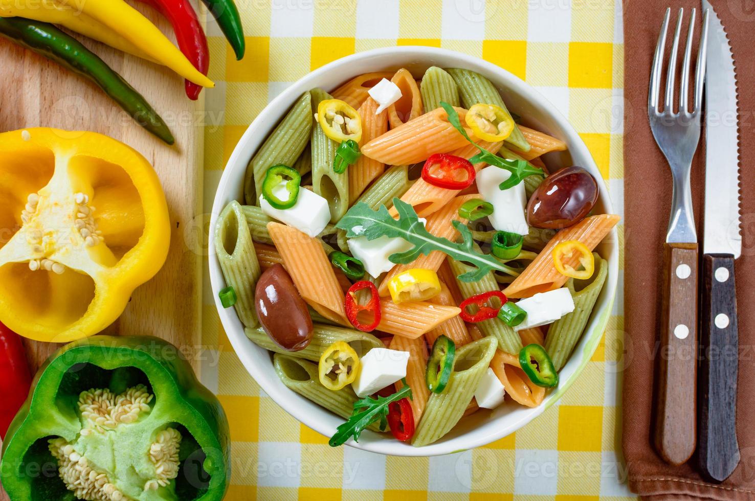 Nudelsalat mit Tomaten, Rucola, Gurken, Paprika, Peperoni, schwarzen und grünen Oliven und Käse-Feta. Ansicht von oben. foto