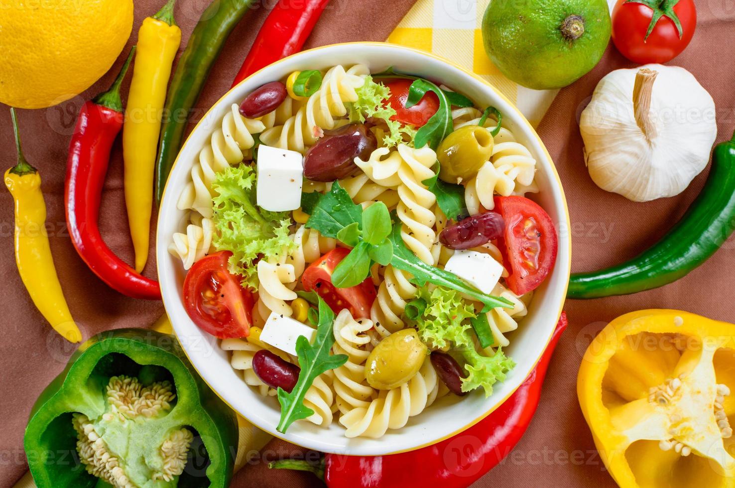 Nudelsalat mit Tomaten, Rucola, Gurken, Paprika, Peperoni, schwarzen und grünen Oliven und Käse-Feta. Ansicht von oben. foto