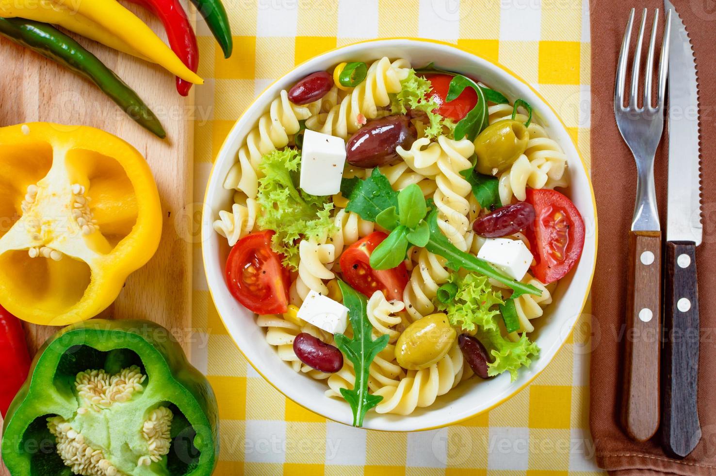 Nudelsalat mit Tomaten, Rucola, Gurken, Paprika, Peperoni, schwarzen und grünen Oliven und Käse-Feta. Ansicht von oben. foto