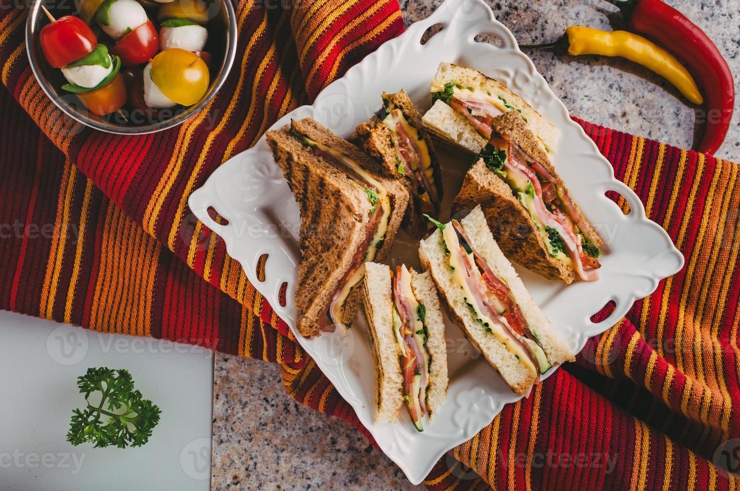 Club-Sandwich mit Schinken, Salami, Räucherfleisch, Käse, Salat und Rucola.Toast-Sandwich-Zubereitung. foto