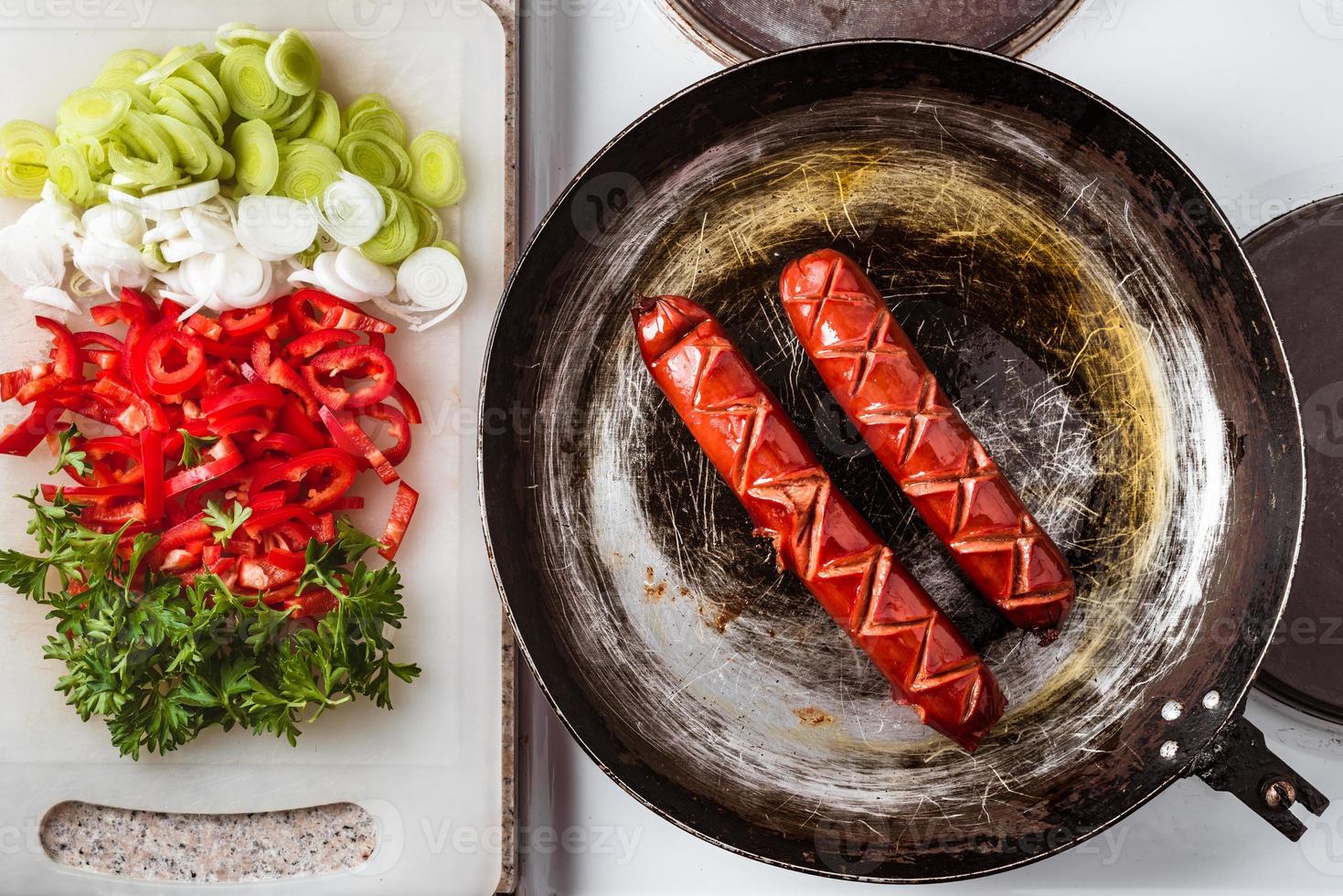 Wurst auf rustikaler Pfanne gebraten, Mischung aus frischem Gemüse, Paprika, Petersilie und Lauch auf Küchenpaneel bereit zum Frittieren. foto